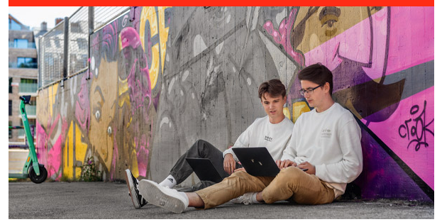 Two men sitting on the ground with laptops

Description automatically generated